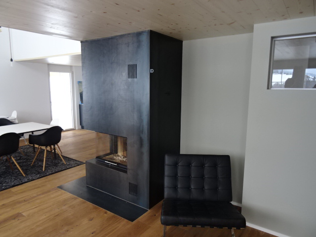 Cheminée-Verkleidung aus dunklem Metall in einem modernen Wohnraum, Sonderanfertigung von Metallbau Gontenbad AG